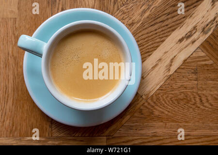 Coffee Americano in Blue ceramic Mug on brown wooden empty Table in Cafe - top View Stock Photo