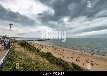Bournemouth, UK. 4th August 2019. Overcast weather with stormy skies doesn't deter the crowds of enjoying Bourneomuth beach and people swimming in the sea. Credit: Thomas Faull/Alamy Live News Stock Photo