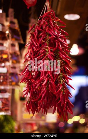Dried red chillies hanging up for sale in market Stock Photo