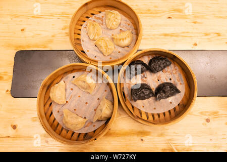White meat, shrimps and mushroom steamed dumplings on a wooden table in a wooden steamer in an asian restaurant or chinese bar with dumplings. Flat Stock Photo