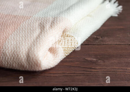 Soft and warm folded wool plaid on wooden background Stock Photo