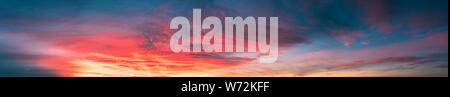 Sunrise Sky Cloudscape. Natural Bright Dramatic Sky In Sunset Dawn. Yellow, Blue And Orange Sky Colors Above Dark Ground Stock Photo