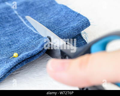 A needle and thread sew up a hole in a denim. Work of a seamstress