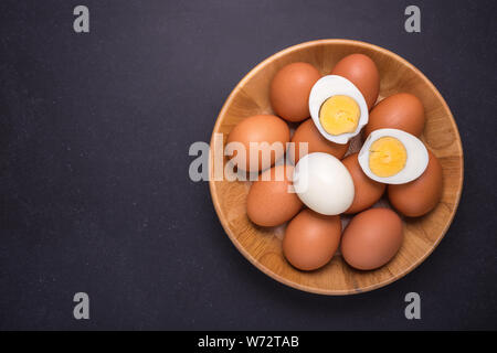 Fresh egg and boiled egg without shell. Top view on black stone background Stock Photo