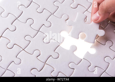 Connection concept : Hand holding pieces of jigsaw puzzle and insert into the missing hole Stock Photo