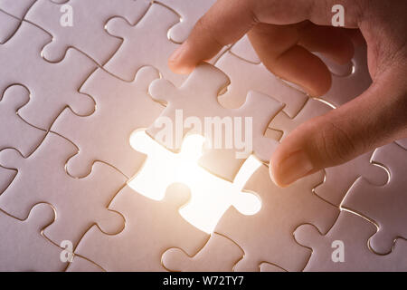 Connection concept : Hand holding pieces of jigsaw puzzle and insert into the missing hole Stock Photo