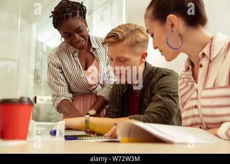 Positive delighted international tutor consulting her students Stock Photo