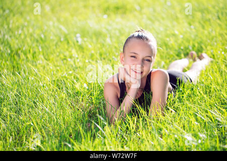 Cute happy little girl lying on the grass. Stock Photo