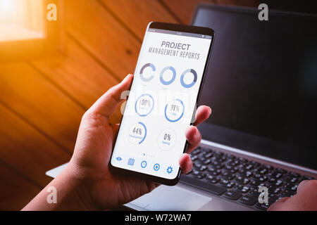 Project management dashboard reports data analytics concept. Close up of young business woman holding smart phone with project management dashboard re Stock Photo