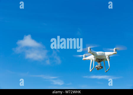 Flying drone quadcopter with digital camera on blue sky background Stock Photo
