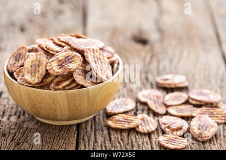 Traditional thai style snack. Sweet and dry sliced banana on wooden table Stock Photo