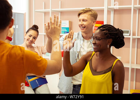 Positive delighted international young people touching hands Stock Photo