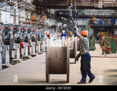 Wire rod, fittings in warehouses. worker alongside a bundle with catalkoy. industrial storehouse at the metallurgical plant Stock Photo