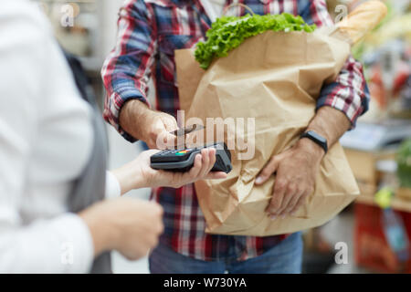 Mid section portrait of young man paying via smartphone at farmers market, copy space Stock Photo