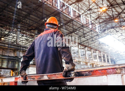 A man in a working form on the background of a metallurgical plant. tired of work worker Stock Photo