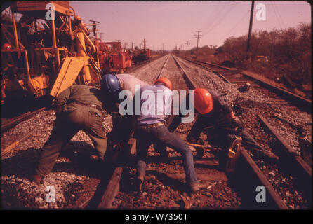 SOUTHERN RAILWAY RIGHT-OF-WAY WORK CREW JACK UP A RAIL THEY ARE REMOVING OLD TIES AND REPLACING THEM WITH NEW ONES WHILE IMPROVING THE ROADBED. THE MAXIMUM SAFE SPEED FOR VIRTUALLY ALL THE COMPANY'S 10,531 MILES OF TRACK IS 60 MILES PER HOUR. THAT CONTRASTS WITH ANOTHER COMPANY WHICH HAD SOME TRACK WITH A SAFE SPEED MAXIMUM OF EIGHT MILES PER HOUR. IN 1974 SOUTHERN SPENT 18.6 PERCENT OF ITS REVENUE ON TRACK MAINTENANCE Stock Photo