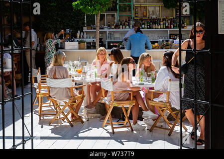 Group of beautiful young women sat at tables chatting and drinking cocktails in Visby, Gotland, Sweden on 20 July 2019 Stock Photo