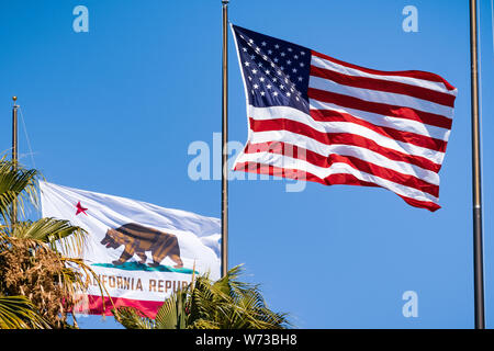 August 1, 2019 Santa Clara / CA / USA - Beautifully waving star and striped American flag and the Republic of California flag on a blue sky background Stock Photo