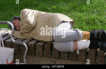 Homeless beggar sleeps on a bench in Moscow Stock Photo