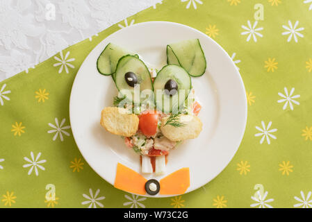 Creatively decorated salad in the form of a hare. Children's menu on a green background Stock Photo