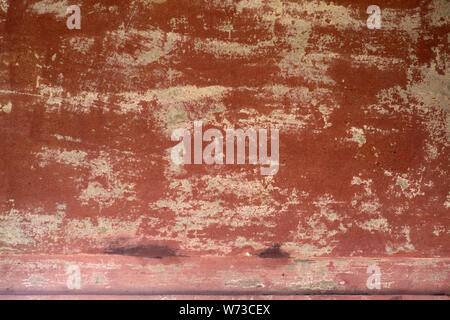 The close-up of peeling clay colored wall paint on a wall. Stock Photo