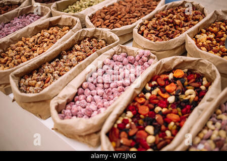 Close up of small bags with nuts. Inside the paper bags are dried fruits, nuts, dates, figs, raisins.  Nuts and dried fruits at the market. Stock Photo