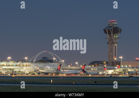 Image of the Theme Building, control tower, and Delta Air Lines jets at the gate, in the Los Angeles International Airport, LAX, at dusk. Stock Photo