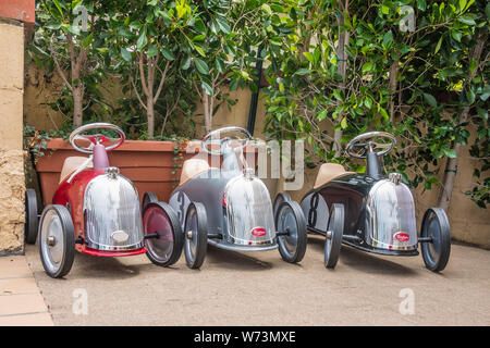 Three Baghera Ride-On Cars for Kids displayed outside a shop in Montecito, California. The cars are designed in France on a design from the 1950's. Stock Photo