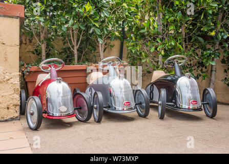 Three Baghera Ride-On Cars for Kids displayed outside a shop in Montecito, California. The cars are designed in France on a design from the 1950's. Stock Photo