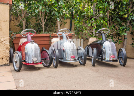 Three Baghera Ride-On Cars for Kids displayed outside a shop in Montecito, California. The cars are designed in France on a design from the 1950's. Stock Photo