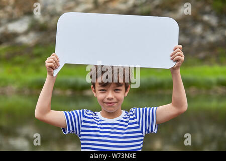 White active boy about 8 years old is holding blank sheet of paper in his hands and smiling. Stock Photo