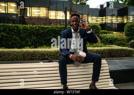 African American businessman holding mobile phone wearing blue suit Stock Photo