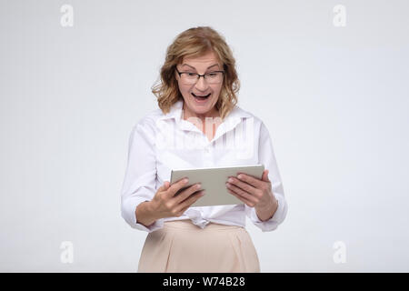 Laughing senior woman using tablet computer to buy some stuff Stock Photo
