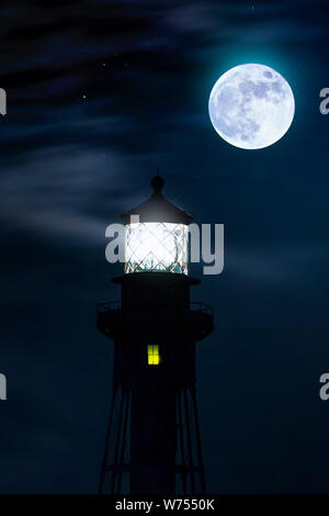 A full moon glows brightly over the Hillsboro Inlet Lighthouse in South Florida. Stock Photo