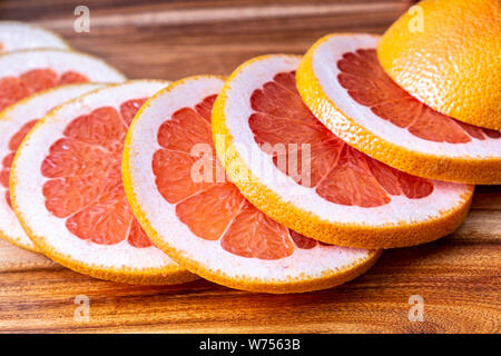 Red grapefruit slices on wooden cutting board Stock Photo