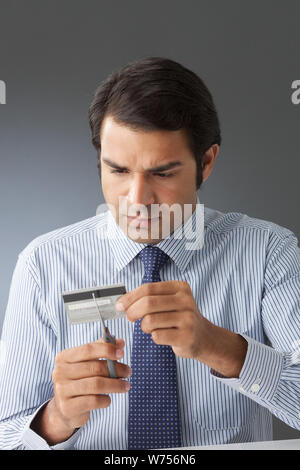 Businessman cutting a credit card with scissors Stock Photo