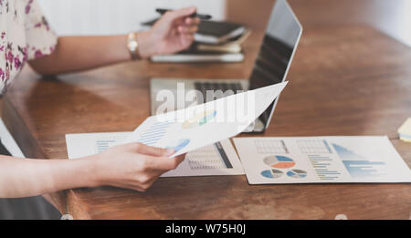 Hardworking young businesswoman analysing her strategy on marketing plan with charts and graphs Stock Photo