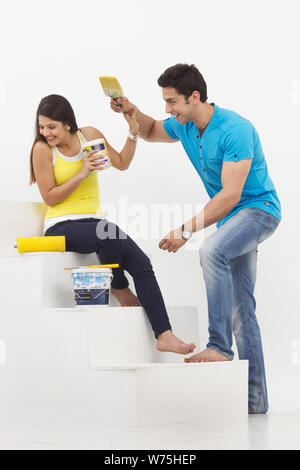 Indian young couple having fun while painting their home Stock Photo