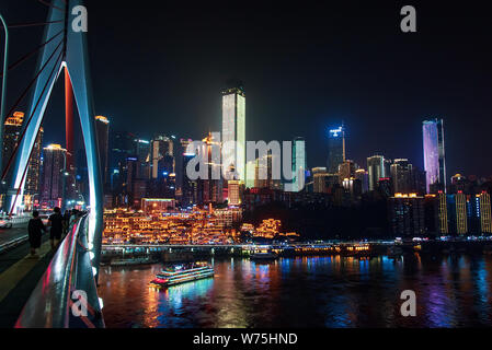 Chongqing, China - July 23, 2019: Urban skyline of Chongqing with Hongya cave and modern skyscrapers from the Chaotianmen bridge over Yangtze river in Stock Photo