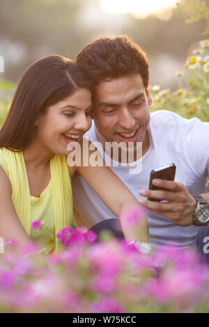 Couple using mobile phone in park Stock Photo
