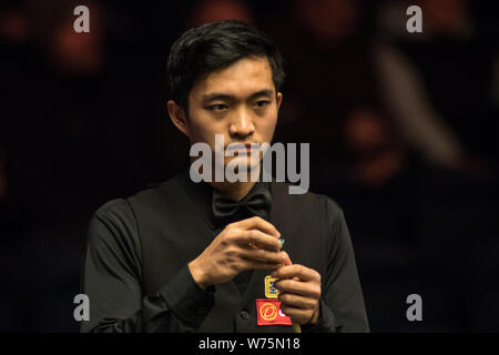 Fang Xiongman of China chalks his cue as he considers a shot to Marco Fu of Hong Kong in their second round match during the 2017 Dafabet Scottish Ope Stock Photo