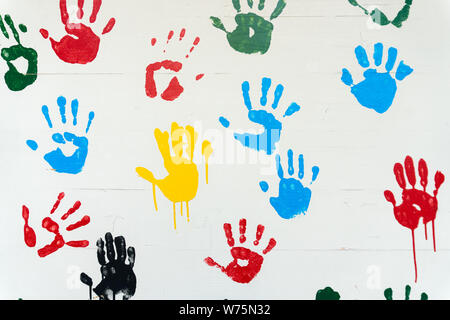 many sets of bright cheerful handprints in many colors on a white background Stock Photo