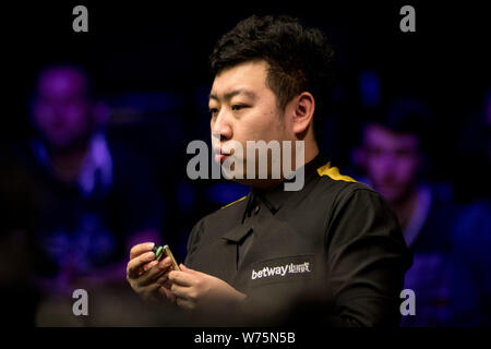 Li Hang of China chalks his cue as he considers a shot to Ryan Day of Wales in their fourth round match during the 2017 Betway UK Championship snooker Stock Photo