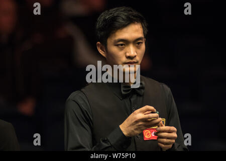 Fang Xiongman of China chalks his cue as he considers a shot to Marco Fu of Hong Kong in their second round match during the 2017 Dafabet Scottish Ope Stock Photo