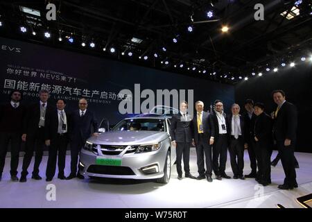 Executives and guests of National Electric Vehicle Sweden (NEVS) pose with the first NEVS 9-3 series EV during the off-line ceremony at Tianjin Binhai Stock Photo