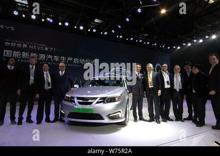 Executives and guests of National Electric Vehicle Sweden (NEVS) pose with the first NEVS 9-3 series EV during the off-line ceremony at Tianjin Binhai Stock Photo