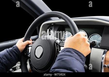 Male hands holding car steering wheel. Hands on steering wheel of a car driving. Young Man driving a car inside cabin. Multimedia system. Man Travelin Stock Photo