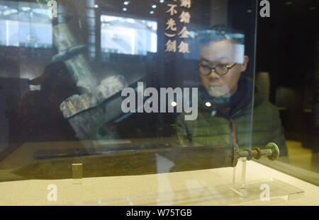A visitor looks at a bronze sword of King Goujian of Yue (reigned 496 BCE - 465 BCE) inlaid with gold and silver on display at Xilin Yingshe Auction's Stock Photo