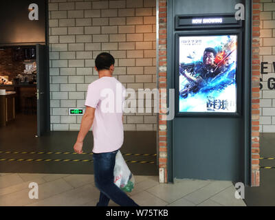 --FILE--A Chinese film goer looks at a poster of the Chinese action movie "Wolf Warriors 2" displayed at a cinema in Shanghai, China, 9 August 2017. Stock Photo