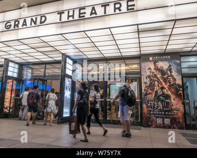 --FILE--Chinese film goers walk past a poster of the Chinese action movie "Wolf Warriors 2" displayed at a cinema in Shanghai, China, 9 August 2017. Stock Photo